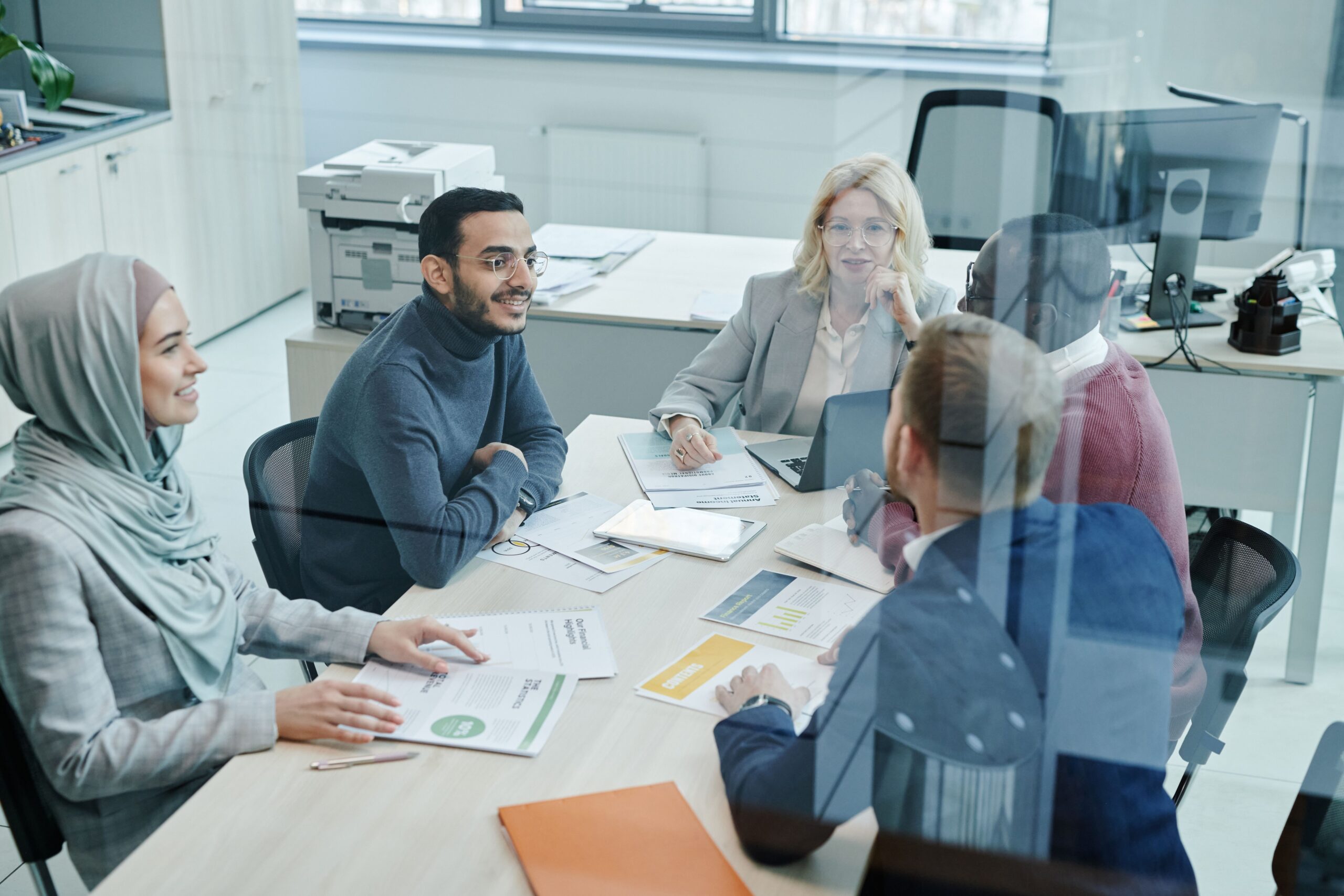 Grow Your Business Through Meaningful Connections A diverse group of professionals engaged in a meeting at a modern office, promoting teamwork and collaboration.