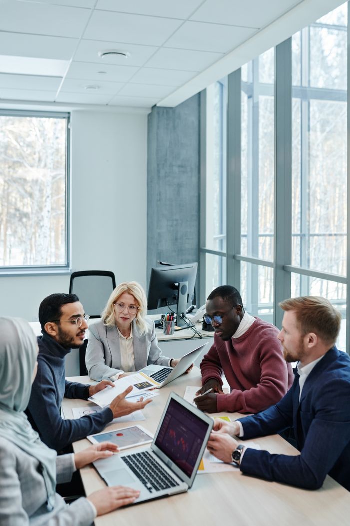 Services A diverse group of colleagues working together on a project in a bright, modern office environment.