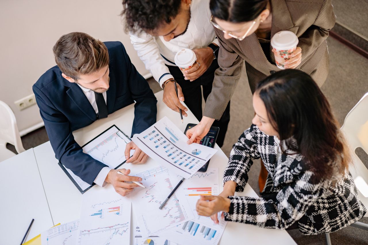 About A diverse team in business attire collaborates over graphs and charts for a successful project.