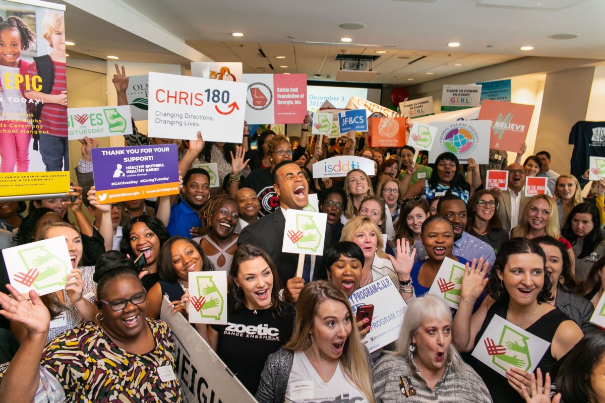 pexels photo 9826015 9826015 A lively gathering of people indoors celebrating a charity event with various signs and expressions of joy.